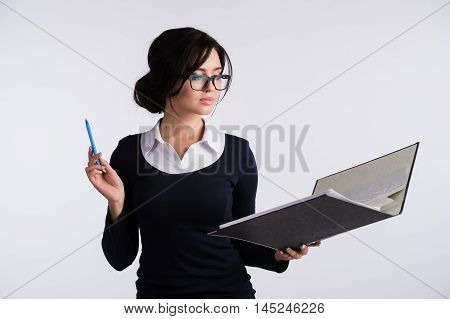 Young Caucasian woman wearing a dark blue dresst and and a white shirt, holding a ring binder folder and pen. Isolated on light background