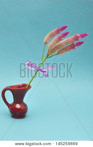 Purple flowers tied with a purple bow displayed in a maroon flower pot isolated on a blue background
