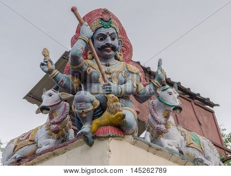 Madurai India - October 19 2013: Closeup of male Gana keeping guard on the corner of the Meenakshi Temple wall. Two bulls keep him company.