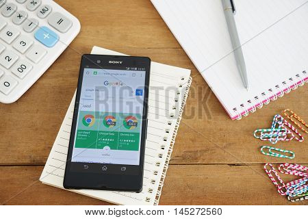 PHUKET, THAILAND AUG 18 2016 : Mobile phone with Google app on the splite screen and old wood desk with notepad and calculator Most of its profits are derived from AdWords