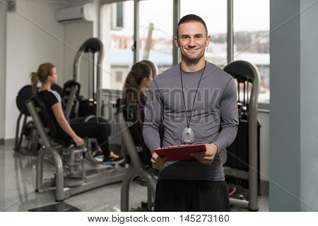 Personal Trainer Takes Notes While Woman Exercising Legs