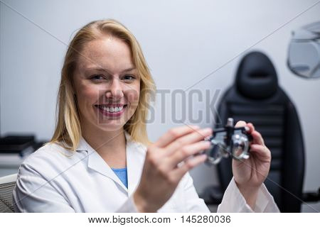 Portrait of smiling female optometrist holding messbrille in ophthalmology clinic