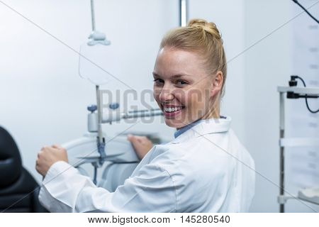 Smiling female optometrist adjusting phoropter in ophthalmology clinic