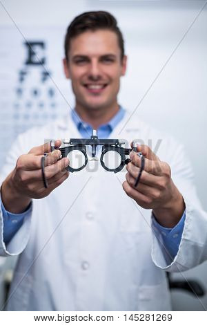 Portrait of smiling optometrist holding messbrille in ophthalmology clinic