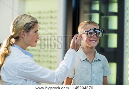 Female optometrist examining young patient with phoropter in ophthalmology clinic