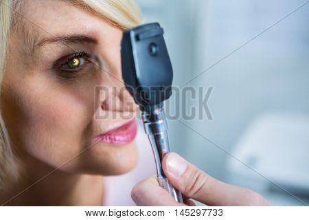 Optometrist examining female patient through ophthalmoscope in ophthalmology clinic