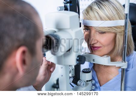 Optometrist examining female patient on slit lamp in ophthalmology clinic