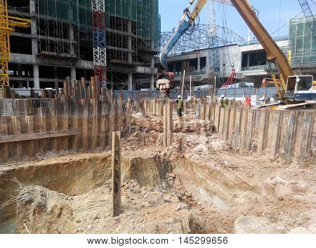 SELANGOR, MALAYSIA -MARCH 25, 2015: Sheet pile cofferdam driven machine at the construction site. The machine drove the sheet pile to the earth using vibrated hydraulic arm. Workers control.