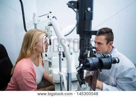 Optometrist examining female patient on coreometry in ophthalmology clinic