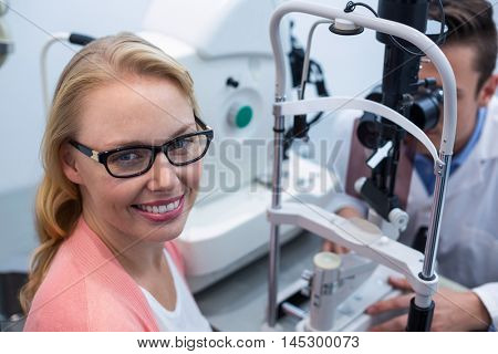 Optometrist examining female patient on slit lamp in ophthalmology clinic