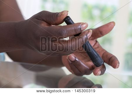 Hand of a woman using lancelet on finger