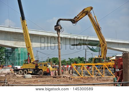 SELANGOR, MALAYSIA -MARCH 25, 2015: Sheet pile cofferdam driven machine at the construction site. The machine drove the sheet pile to the earth using vibrated hydraulic arm. Workers control.