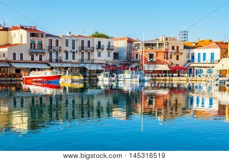 RETHYMNO GREECE - OCTOBER 16 2013: The mirror reflection of the tourist boats and old colorful cottages in waters of the old harbor on October 16 in Rethymno.