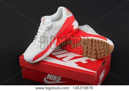 BURGAS BULGARIA - AUGUST 29 2016: Nike Air MAX lady's - women's shoes - sneakers - trainers in white and orange illustrative editorial over Nike shoes box on dark background