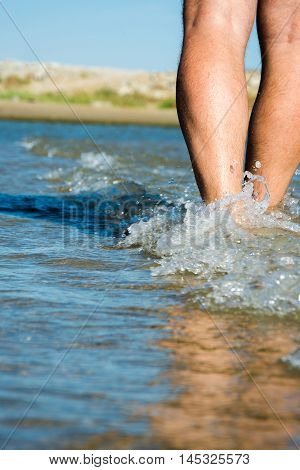 man walking barefoot on seacoast at bright sunny day