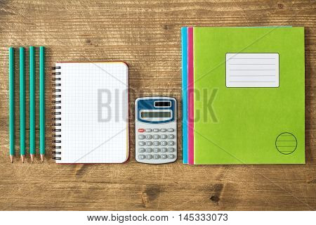 Digital calculatoropen notebookexercise books and pencils.Top view.
