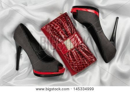 Red lacquer bag and shoes with toeless on a white crumpled fabric