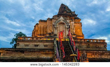 Illuminated Chedi Luang Pagoda at Wat Chedi Luang Temple with cloudy sky at sunset. Popular landmark in Chiang mai, Thailand