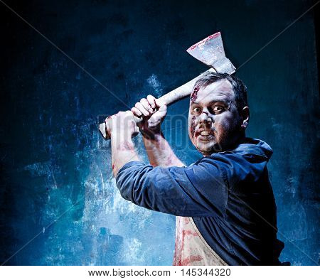 Bloody Halloween theme: crazy killer as bloody butcher with an ax on dark blue background