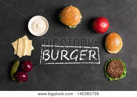 Beef burger with lettuce and minced meat cutlet. Black chalkboard. Top view