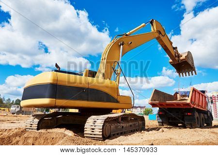 Loader excavator moving earth into dumper truck