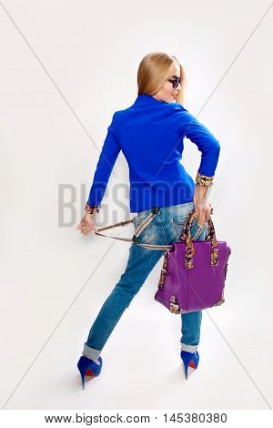 Fashion stylish girl in jeans and a blue jacket rear view sunglasses