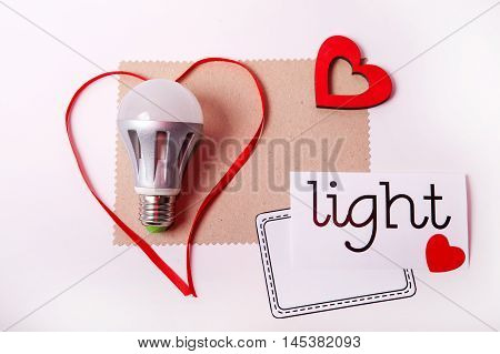 Energy saving lamp and decorative red heart and banner for your text on a white background