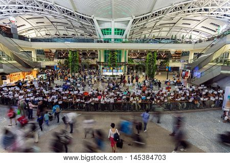 BALI, INDONESIA - AUGUST 3, 2016: A women in the Ngurah Rai International Airport in Bali, Indonesia looks for a taxi driver.