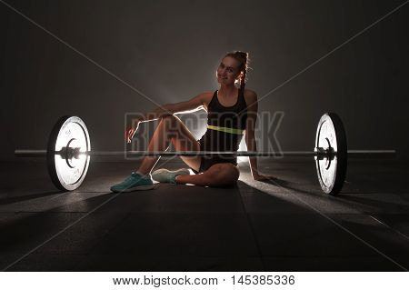 One woman on the floor with barbel. Concept of woman and fitness. Shallow depth of field. Low key.