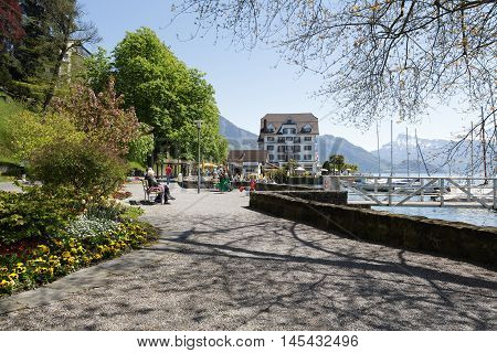 Weggis Switzerland - May 05 2016: Promenade along the shore of Lake Lucerne is the perfect place to spend time and enjoy the beauty of nature. Several people can be seen in a distance. Weggis it is the small holiday resort placed on the shore of Lake Luce