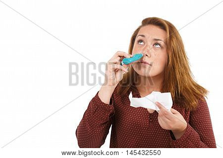 young woman using nose drops isolated on white background. portrait of a girl with a nasal spray and tissue in hands. look upwards. the concept of treatment for allergies or the common cold