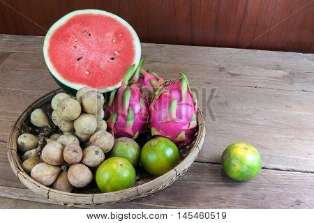 Asian fresh fruits. Langsat and watermelon and Orange and Dragon fruit in bamboo basket.