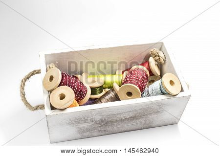 A wooden box with some spools with ribbon