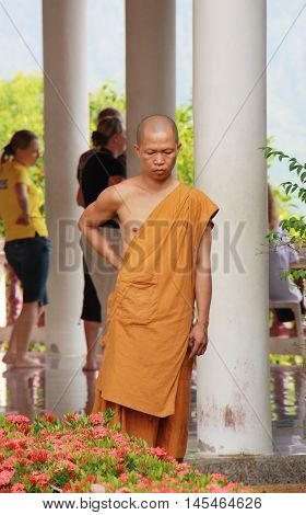 A Buddhist monk lost in thought looking at the flowers