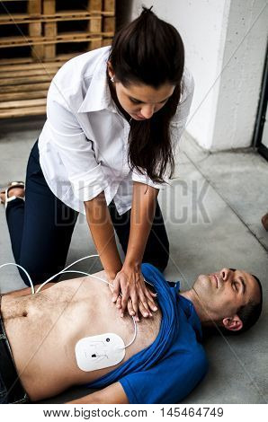 girl assisting an unconscious man with cardiopulmonary resuscitation