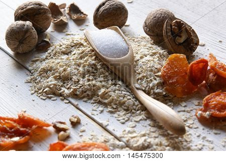 Ingredients for dietary recipe oatmeal cookies: oatmeal, erythritol (erythritol), dried fruits, nuts. Om white rustic wooden table.