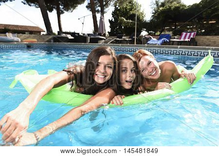 group of three happy and beautiful young girl friends having bath floating in airbed in swimming pool together having fun enjoying summer at vacation resort smiling in women holiday concept