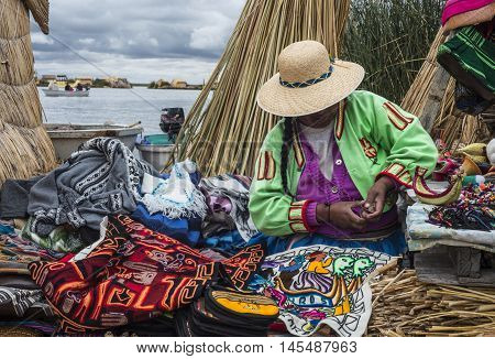 Uros Floating Islands Titicaca Peru - December 14 2014: Unrecognizable woman in national costume Indian Uros knits a sheaf