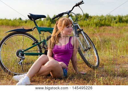 beautiful woman resting sitting on the grass with bicycle