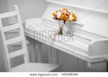 orange bouquet orchid on white piano near chair