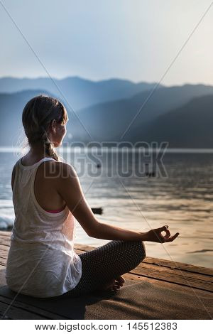 Young woman meditating by the lake sunset water birds