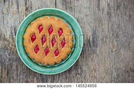 Biscuits with jam on a green plate. Old wooden background. Copy space.