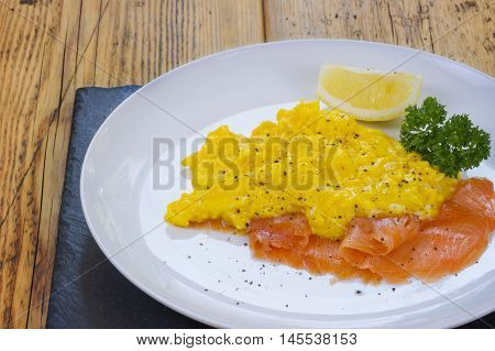 Scrambled eggs and salmon with lemon and parsley on the side