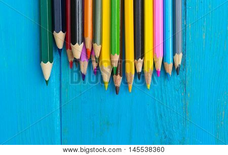 Colored pencils on a blue wooden background. Copy space