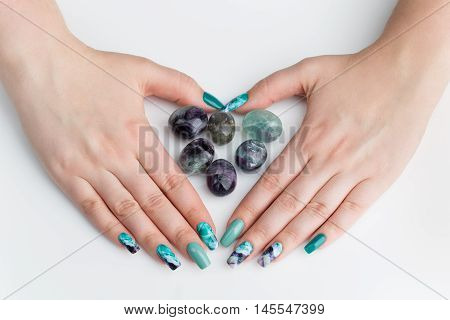 Closeup of woman nails with creative purple and green manicure. Fluorinit print. Copy space.