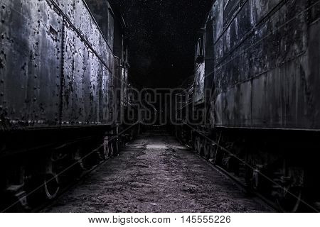 Cemetery of old steam locomotives at night.