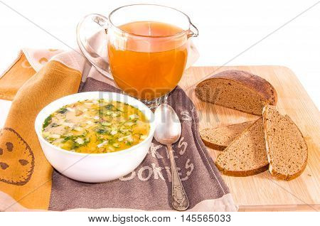 Traditional russian summer cold kvass soup okroshka with chopped potatoes eggs fresh cucumber radish green onion and sausage with greens in a white ceramic bowl jug with kvass (kvas) and black rye bread on wooden cutting board. Healthy food concept. White