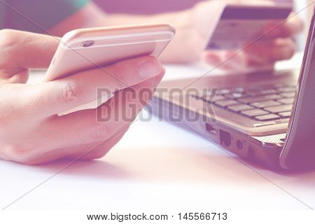 Online paymentMan using laptop and pay by credit card hands holding smart phone using credit card for online shopping