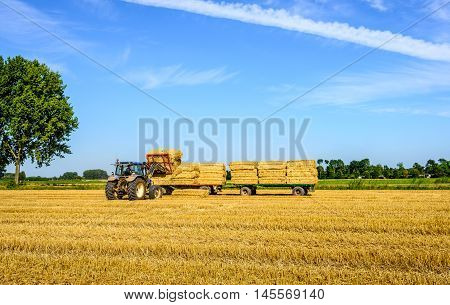 With the coupled pack charger the tractor driver charges loads the collected straw bales on the flat agricultural vehicles.