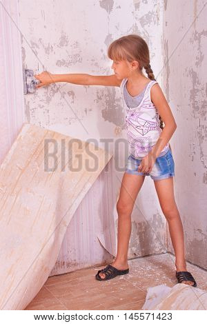 girl remove old wallpapers from the wall